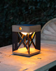 Wooden lantern-style solar lamp on a wooden surface with a blurred natural background by Les Jardins available at Spacio retail stores in Mumbai & Kolkata.  