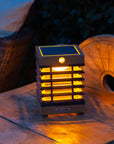 Solar-powered outdoor light on a wooden surface with a blurred background