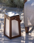 Brown outdoor lantern on a wooden deck with a chair in the background