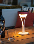Solar lamp on a wooden table with a bottle and glasses, outdoor setting
