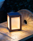 Wooden solar table lamp with warm light on a rustic wooden surface at night by Les Jardins available at Spacio retail stores in Mumbai & Kolkata.  