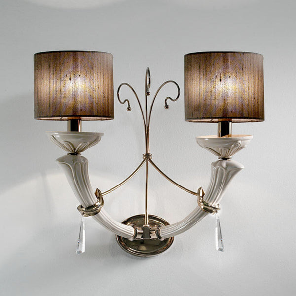 Decorative wall sconce with two lampshades on a plain background by Lorenzon available at Spacio in India. 