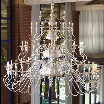 Large white ceramic chandelier in a room with large windows and curtains.