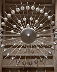 Decorative large ceramic chandelier with metallic spikes and spherical ends on a wooden background