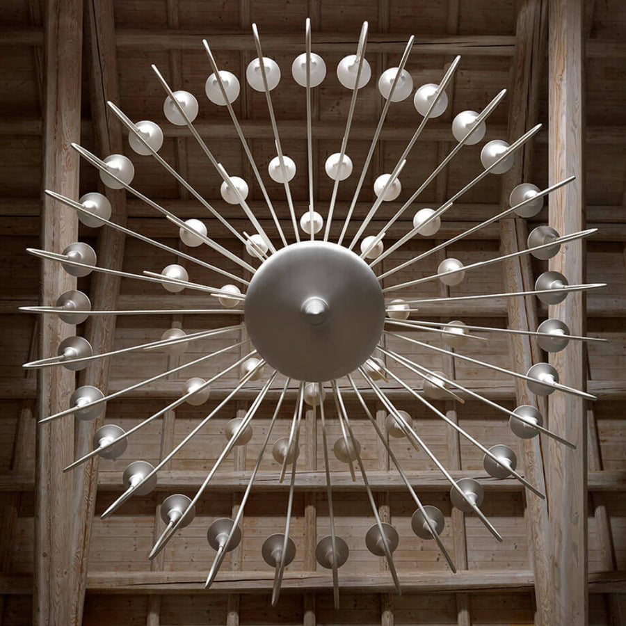 Decorative large ceramic chandelier with metallic spikes and spherical ends on a wooden background
