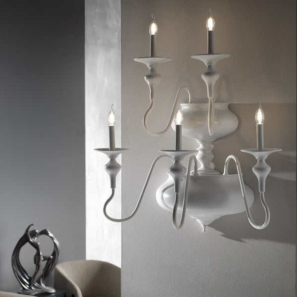 White wall-mounted candle holder with four lit candles against a neutral background from Lorenzon available at Spacio in India.