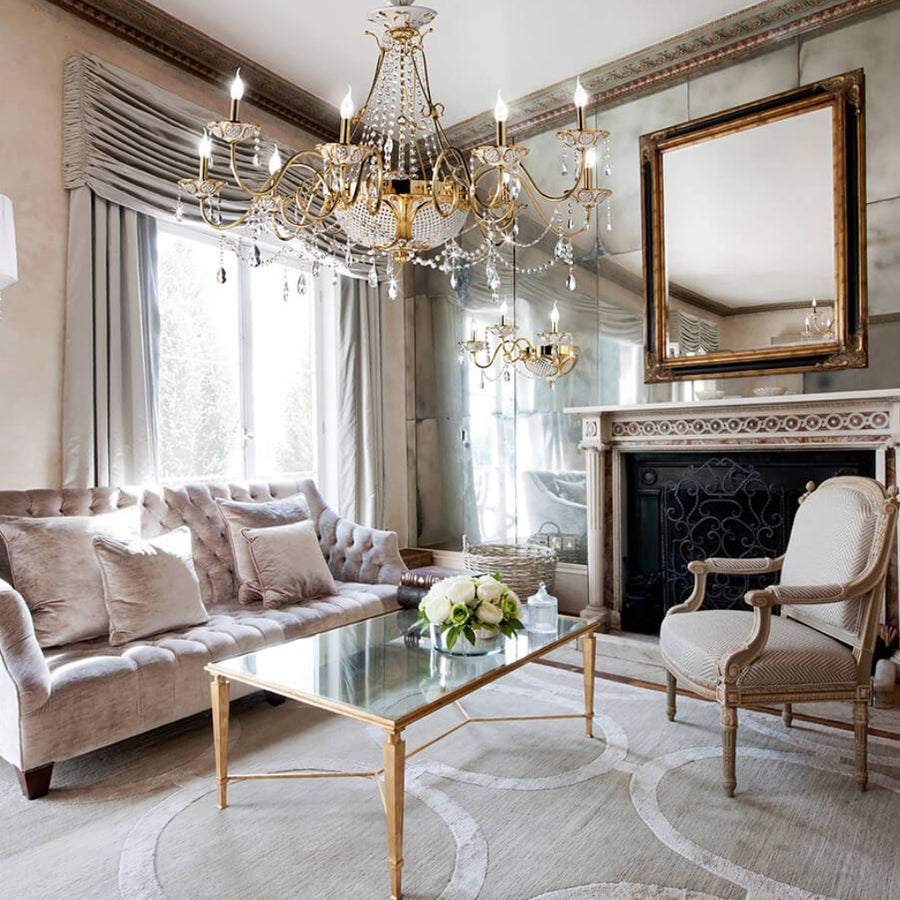 Luxurious living room with a crystal chandelier, sofa, coffee table, and decorative mirror.