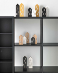 A black ML City Opening B&W (4pc set) bookcase with a collection of house figurines on it, made of beech wood, made by Madlab.