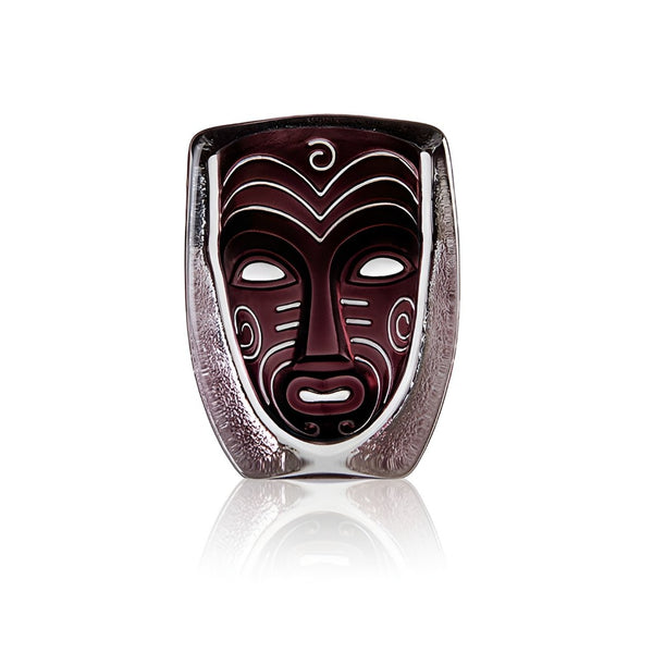 Decorative crystal mask with tribal design in a glass container on a white background