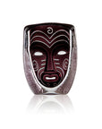 Decorative crystal mask with tribal design in a glass container on a white background