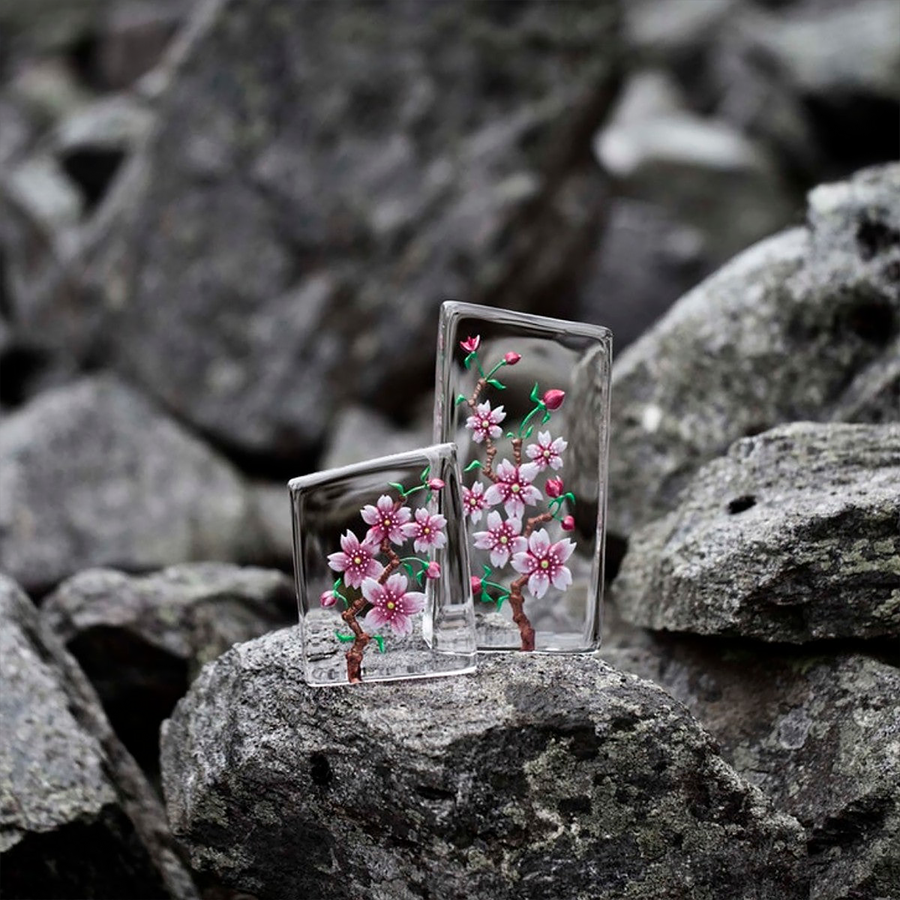 Distant look of Maleras Crystal Sculpture Cherry Blossom Large with other Small sculpture on a Grey stones outdoor back ground available at Spacio India from the Sculptures and Art Objects Collection.