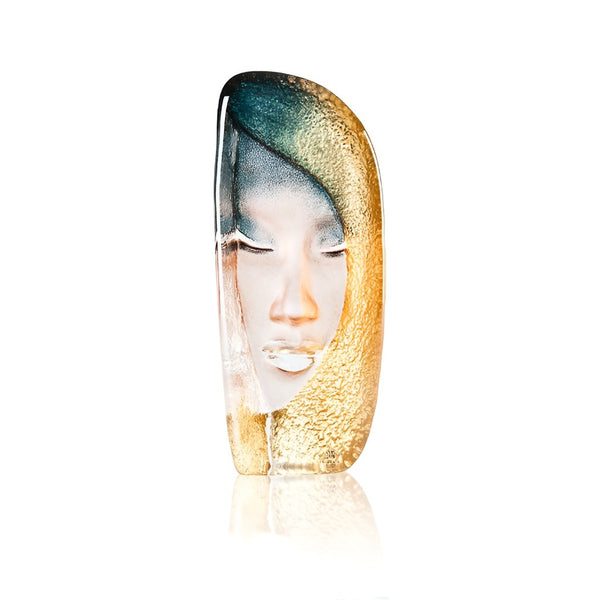Glass sculpture of a face with gold and blue hair on a white background