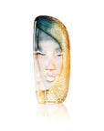 Glass sculpture of a face with gold and blue hair on a white background