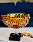 Side look of Mario Cioni Crystal Amber Bowl with Black base on a a wooden table available at Spacio India for luxury home decor accessories collection of Bowls & Centerpieces.