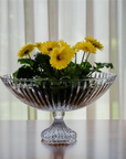 Clear crystal bowl with yellow flowers on a wooden surface