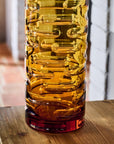 Tall, textured crystal filled with water on a wooden surface