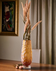 Decorative crystal vase with dried plants on a wooden table, with a blurred background