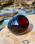 Red crystal decor object with blue and red interior on a rocky surface