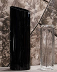Black and clear crystal vases on a textured surface with a patterned background