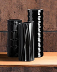 Three black textured crystal vases on a wooden surface with a brown background