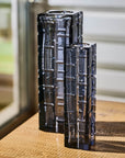 Two black and clear textured crystal vases on a wooden surface with a blurred background