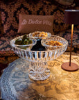 Decorative crystal caviar bowl with snacks on a table with a 'La Dolce Vita' pillow in the background