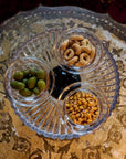 Three small crystal bowls with snacks on a decorative metal tray.