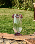 Mario Cioni Cistus Tall Crystal Vase with red flowers, handcrafted in Italy, featuring a cylindrical design and intricate floral details for luxury interiors. Set in a garden outdoor