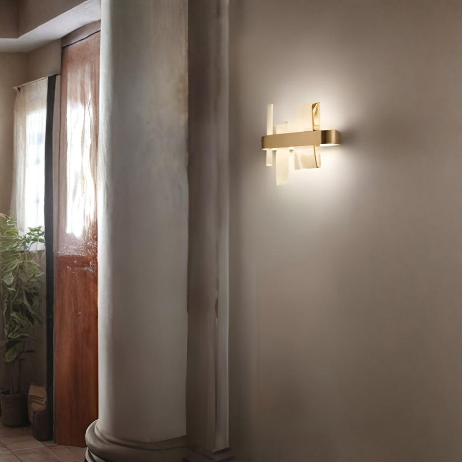 Modern wall sconce on a neutral wall with a plant and wooden door in the background by Masiero available at Spacio retail stores in Mumbai & Kolkata. 