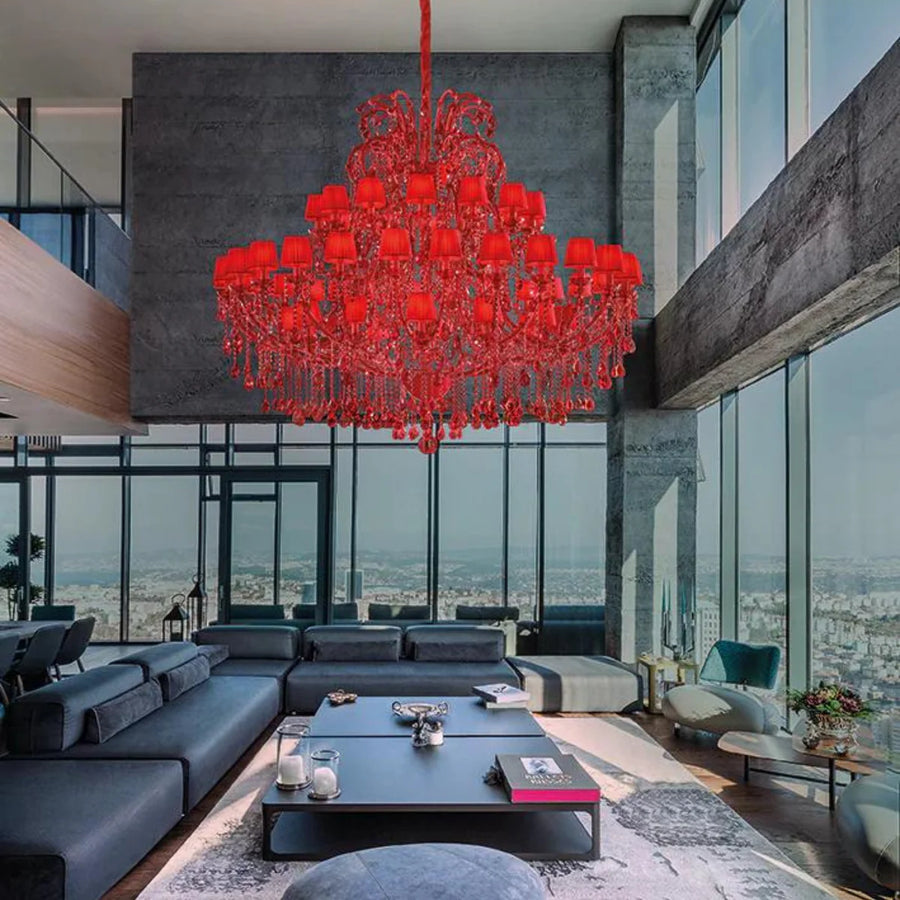 Modern living room with a large red chandelier, gray sofa, and city view.