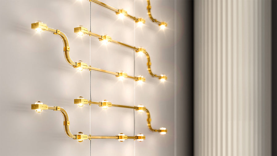 Gold finish decorative modular lights from Masiero hanging against a neutral wall