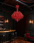 Luxurious bar with a red chandelier, dark brick walls, and a black leather sofa.