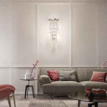 Living room with a gray sofa, red pillows, and a crystal wall light.