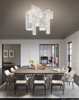 Modern dining room with a large chandelier, table, and chairs.