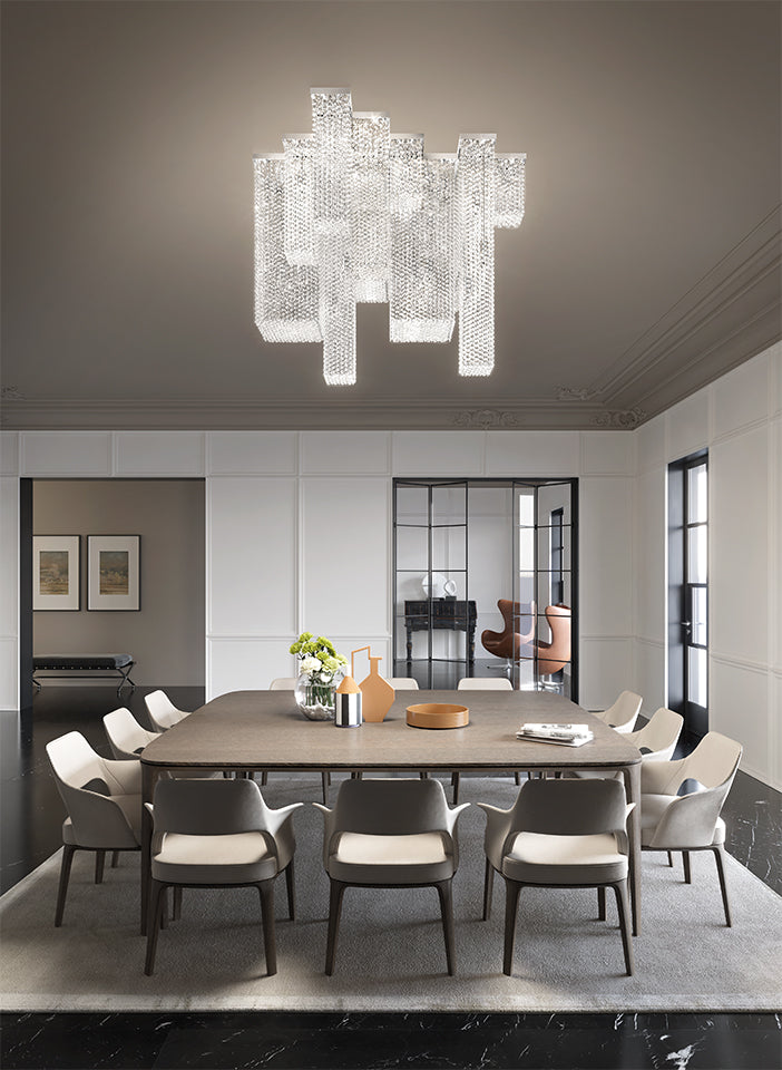 Modern dining room with a large chandelier, table, and chairs.
