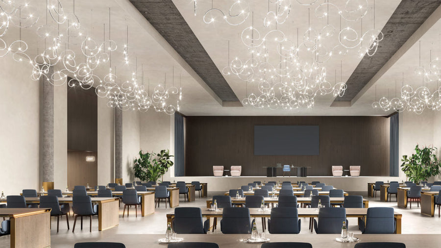 Modern conference room with round tables, chairs, and decorative ceiling lights.