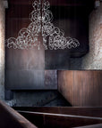 Luxurious chandelier hanging in a dimly lit room with stone walls and wooden accents.