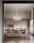 Modern kitchen with a chandelier, island, and pink bar stools.