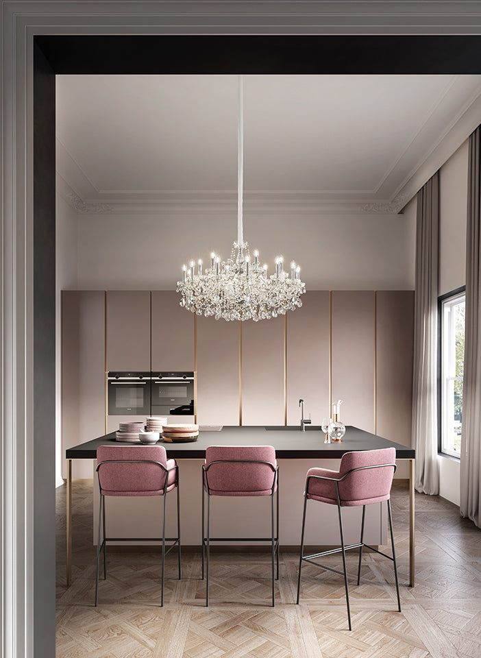 Modern kitchen with a chandelier, island, and pink bar stools.