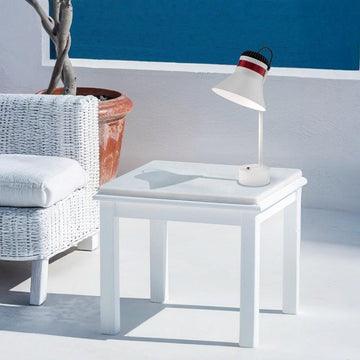 White side table with a rechargeable table lamp from Masiero and plant in a minimalistic room.