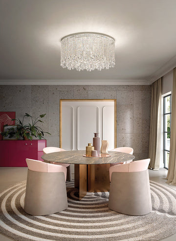 Modern dining room with a round table and chairs, featuring the Cristalle chandelier from Masiero, available at Spacio retail stores in India. 