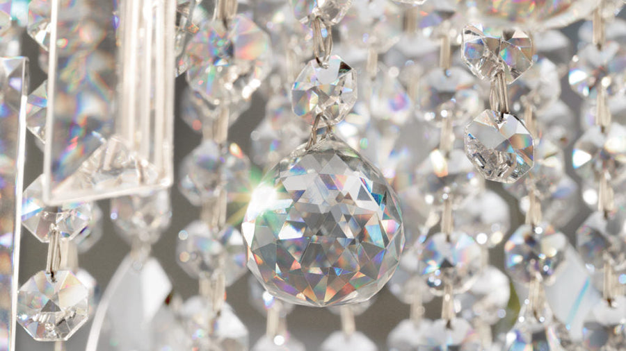 Close-up of a crystal chandelier with clear and multicolored prisms.