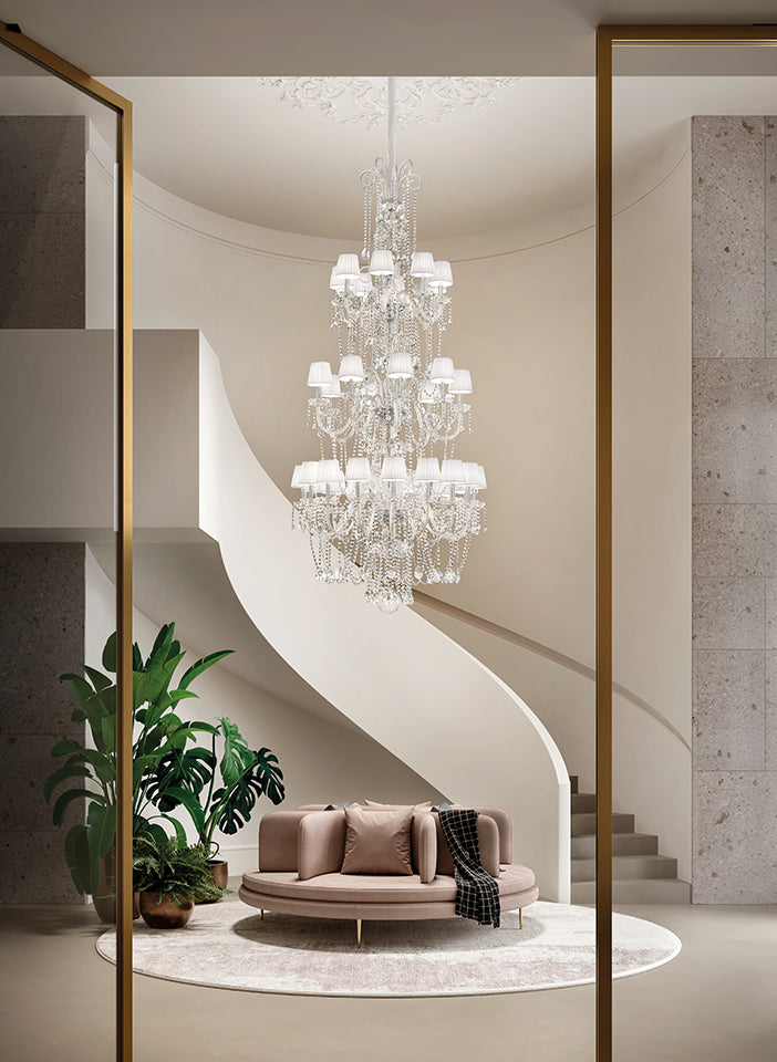 Double height Chandelier hanging above a modern living room with a curved staircase.
