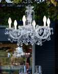 Outdoor crystal chandelier hanging in an outdoor setting with a blurred background