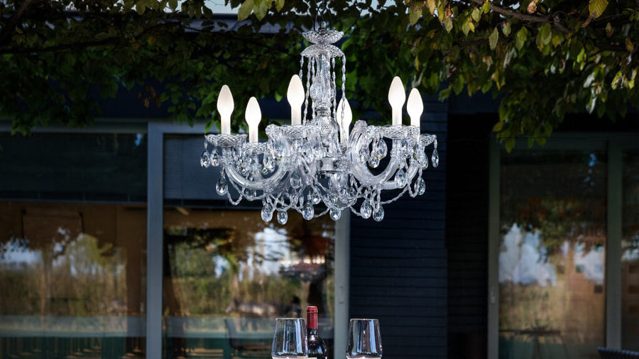 Outdoor crystal chandelier hanging in an outdoor setting with a blurred background