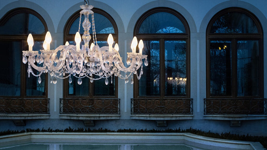 Crystal chandelier hanging above a pool with arched windows in the background