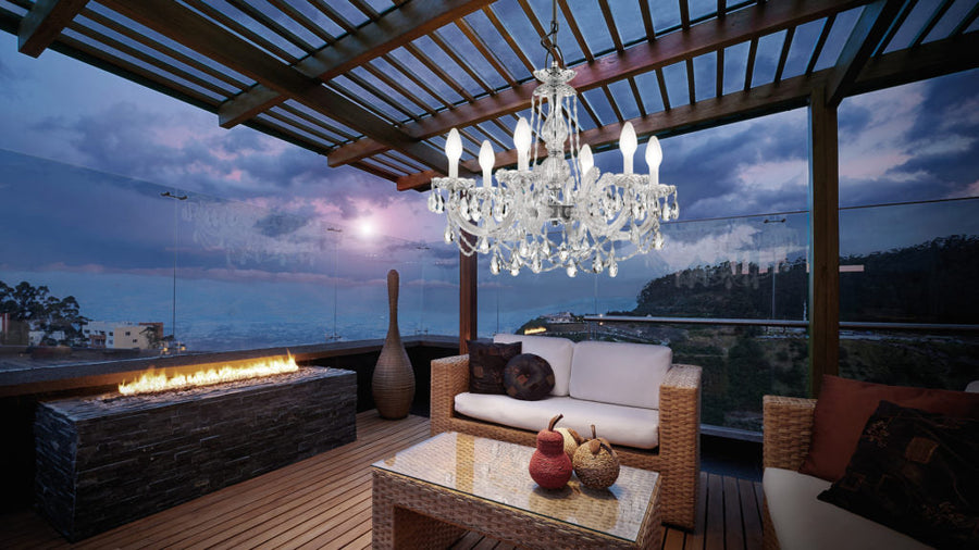 Luxurious outdoor patio with a chandelier, couch, and fire pit at night.