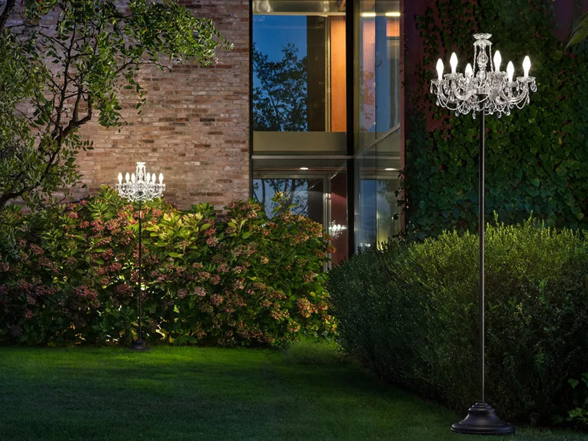 Two outdoor chandelier floor lamp in a garden setting from Masiero's Drylight Collection available at Spacio in India, with a building in the background.