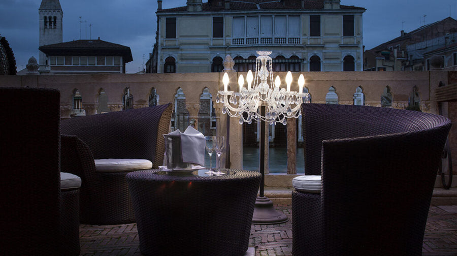 Outdoor seating area with a small floor chandelier and building in the background