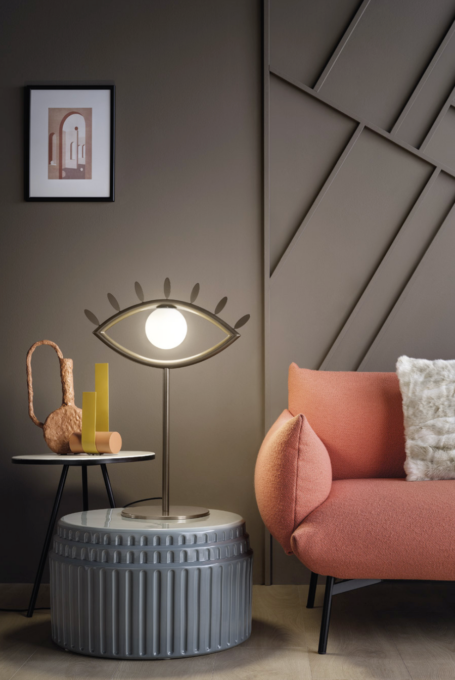 An imagination-evoking living room with the Eye shaped table lamp from Masiero Visio Collection couch and a surrealist lamp, featuring uniquely crafted facial geometries. Styled by Spacio Interior Styling team